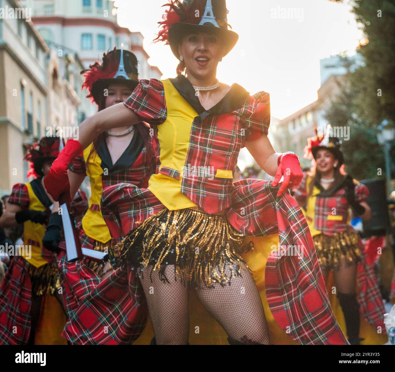 Das Bild zeigt eine Gruppe von Menschen in bunten, koordinierten Kostümen mit einem karierten Schottenmuster. Sie tragen Hüte, haben Bright Stockfoto