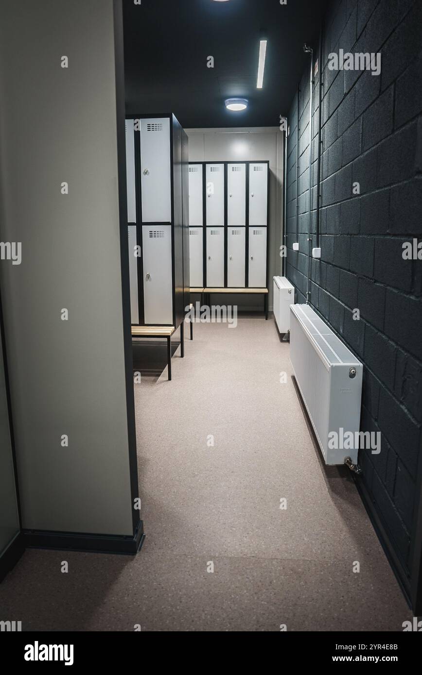 Moderner Schließfachraum mit weißen Schließfächern und Bank in der Sporteinrichtung Stockfoto