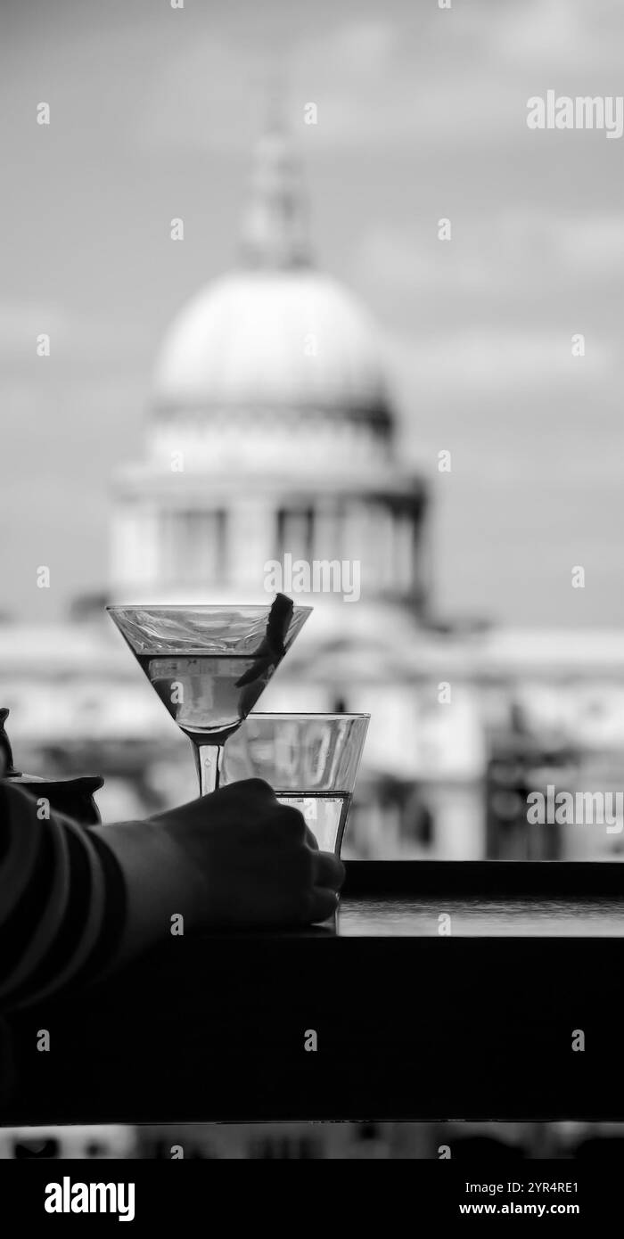 Eine Hand einer Frau mit erfrischendem Cocktail in Martini-Glas mit Zitronengeschmack und einem digitalen Tablet vor einem Blick vom Café der Tate Modern Gallery auf der St. Stockfoto