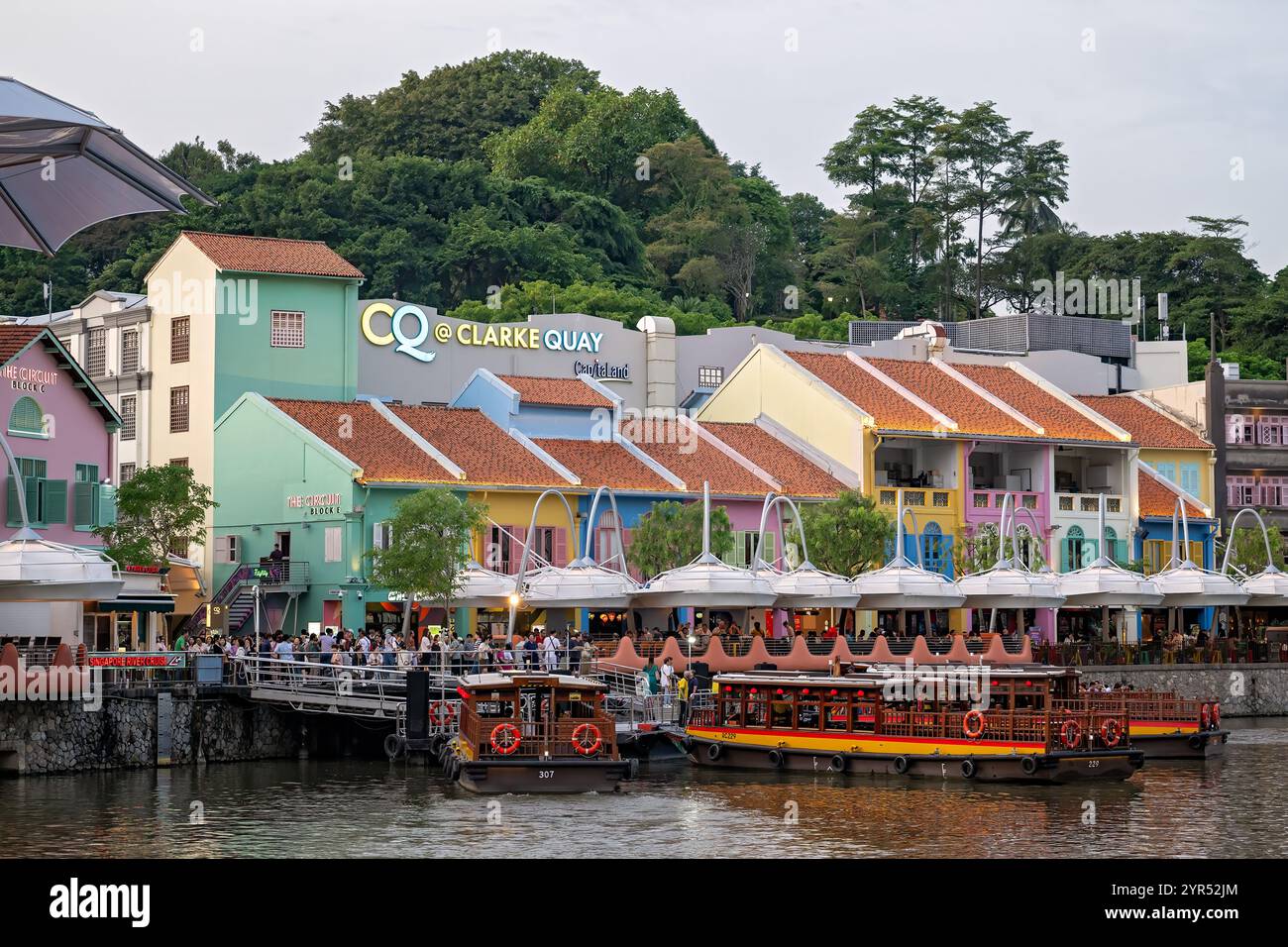 Singapur - 29. Juni 2024: Stadtviertel Clarke Quay, Spaziergang in der Abenddämmerung, beliebtes Touristenziel für Essen und Nachtleben, Bootstour auf dem Fluss Stockfoto