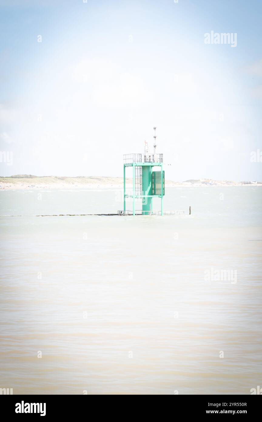 Ein ätherischer Blick auf den Eingang des Rye Harbour in East Sussex mit einem grünen maritimen Schifffahrtsmarker umgeben von ruhigen Gewässern Stockfoto