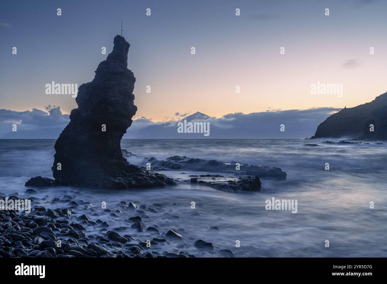 Vor Sonnenaufgang am Strand von Playa de La Caleta. Felsen und Meer. Teneriffa und der Teide im Hintergrund. Lange Belichtung. La Gomera, Kanarische Inseln, Stockfoto