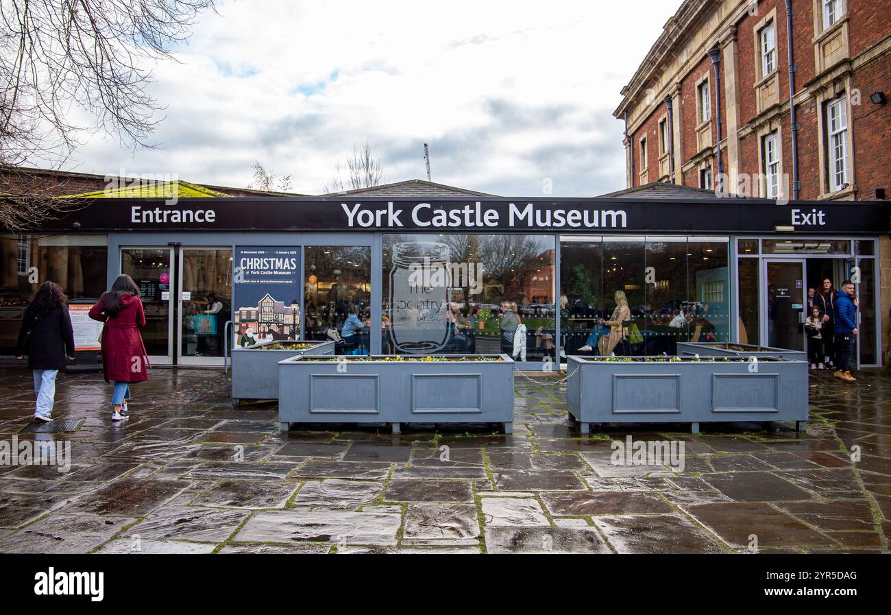 Außenansicht des Eingangs zum York Castle Museum mit Menschen, die auf einem nassen gepflasterten Innenhof unter bewölktem Himmel spazieren gehen, 30. November 2024 Stockfoto