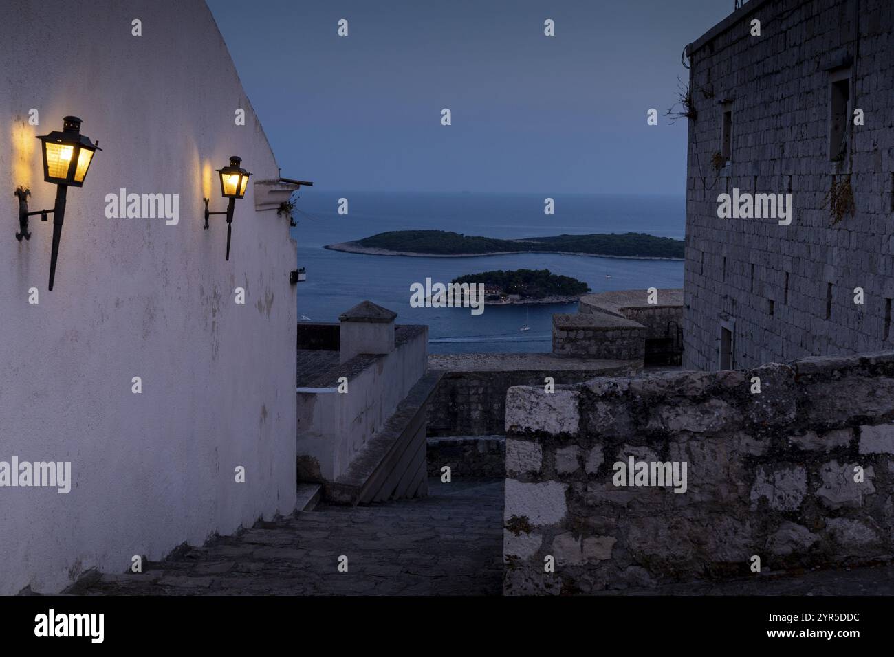 Schmale Gasse mit Laternen und Meerblick in der Abenddämmerung, Hvar, Kroatien, Europa Stockfoto