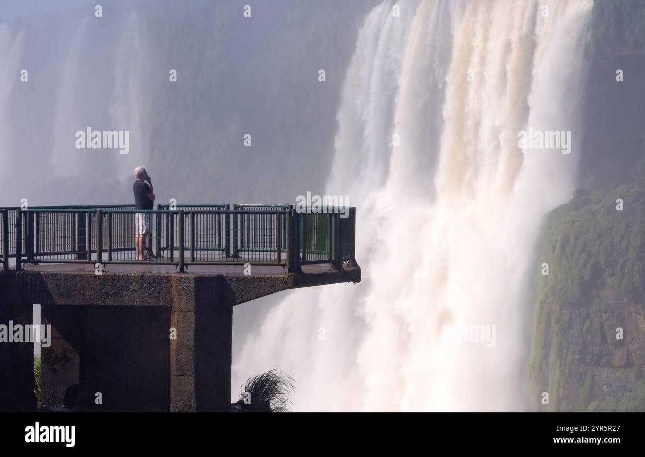 Ein Mann steht auf der Seite von Iguazu Falls Brasilien. Atmosphärisches Foto des Wasserfalls und der Kraft der Natur des Wassers; Brasilien Südamerika Stockfoto