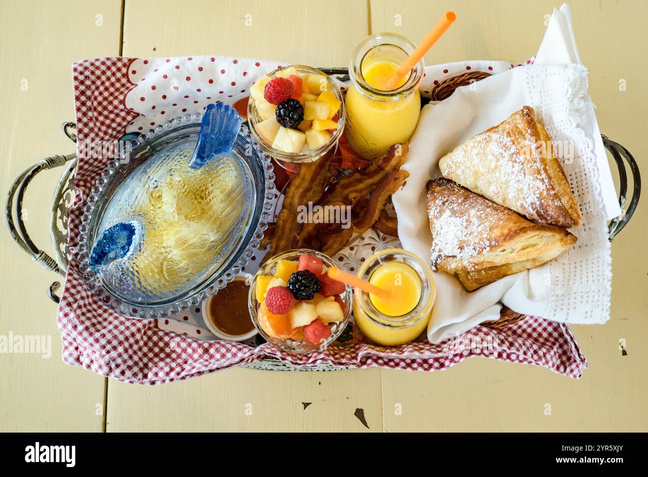 Rustikaler Frühstückskorb mit Gebäck, frischem Obst und Orangensaft Stockfoto