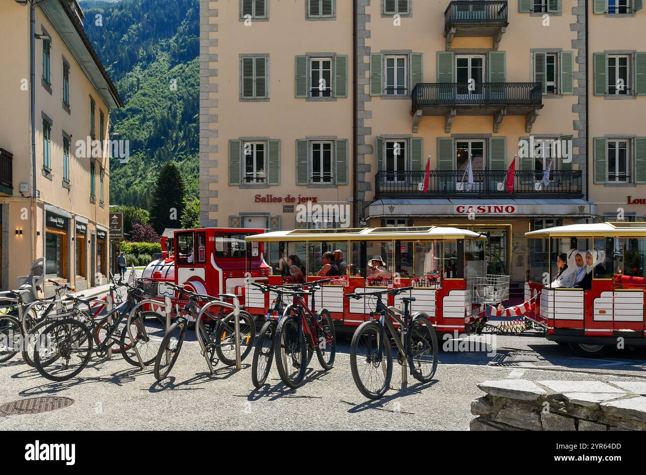 Ein roter Touristenzug, der vor dem Casino Le Royal fährt, historisches Spielhaus im Zentrum der Bergstadt, im Sommer Chamonix, Frankreich Stockfoto