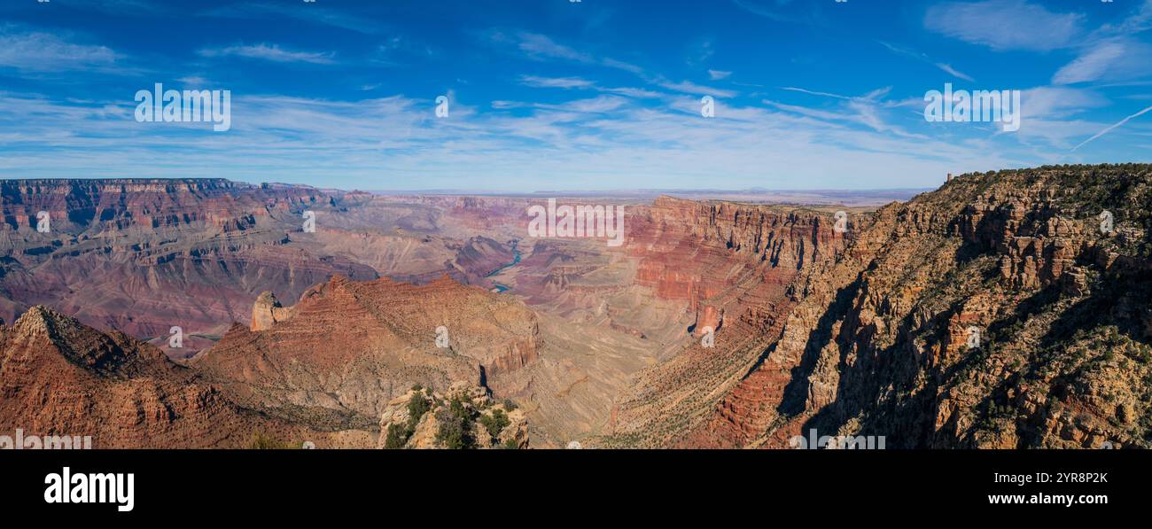 Panoramarischer Weitwinkelblick auf die weiten roten Felsschluchten und geschichteten Klippen des Grand Canyon unter einem blauen Himmel mit sanften weißen Wolken, Arizona Stockfoto