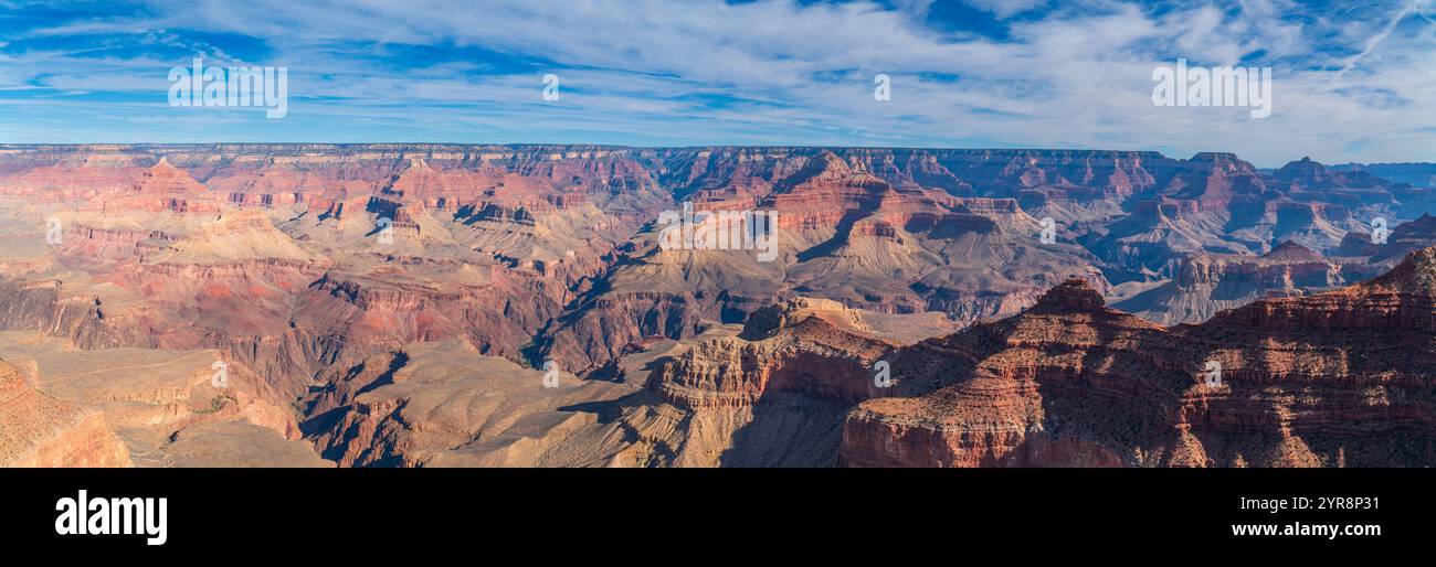 Panoramarischer Weitwinkelblick auf die weiten roten Felsschluchten und geschichteten Klippen des Grand Canyon unter einem blauen Himmel mit sanften weißen Wolken, Arizona Stockfoto