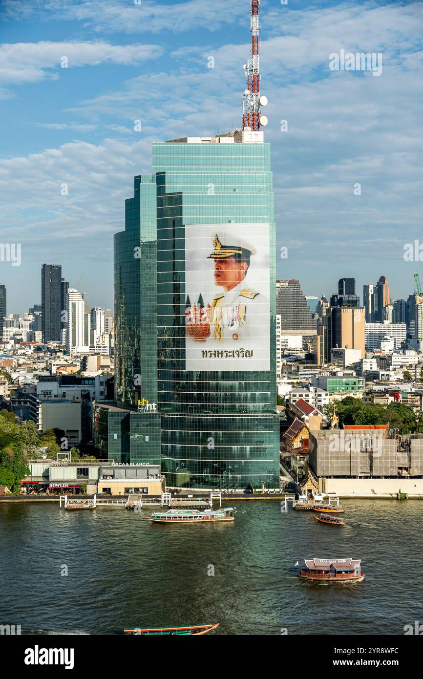 Majestätische Skyline von Bangkok mit einer Hommage an den König über belebten Gewässern Stockfoto