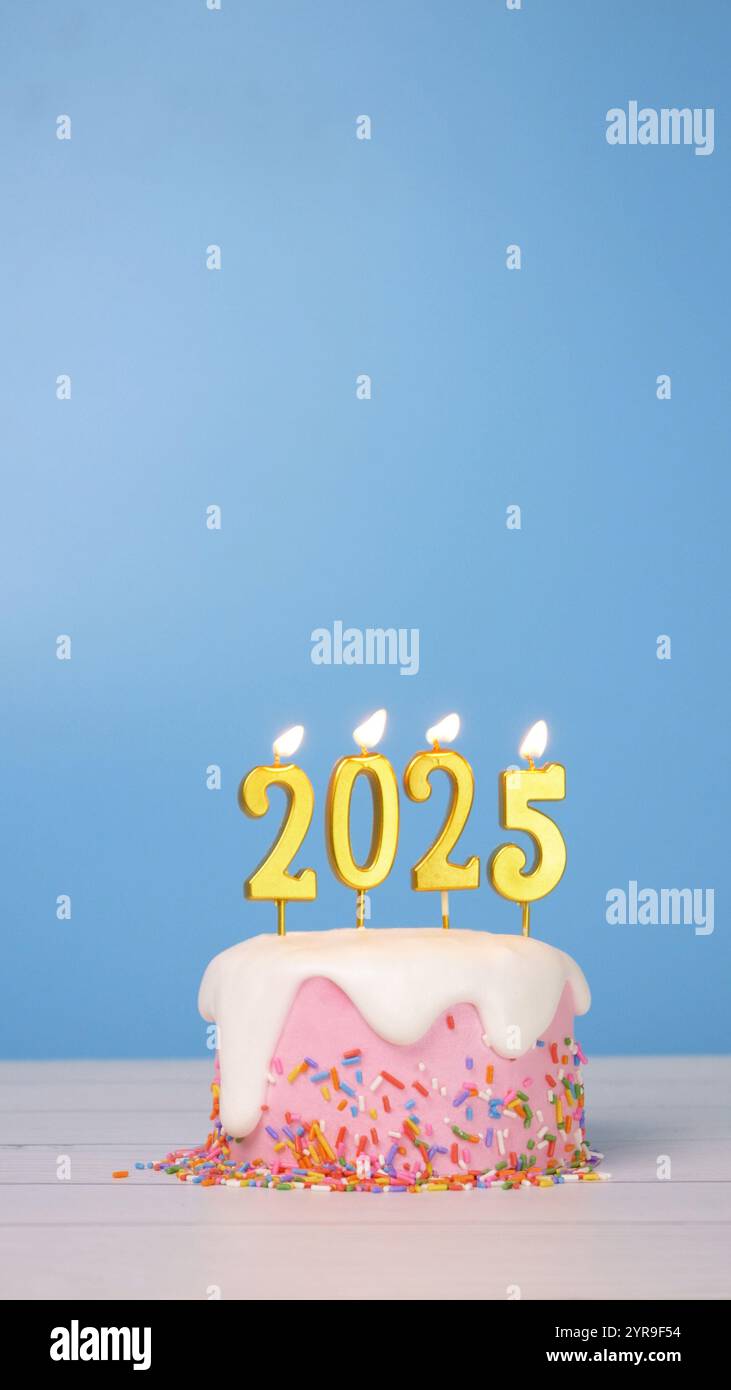 Frohe Neujahrsfeier 2025, süßer Kuchen mit goldener Kerze Nummer 2025 für die Neujahrsfeier wurde angezündet. Flamme am Kerzenwickel mit blauem Hintergrund Stockfoto