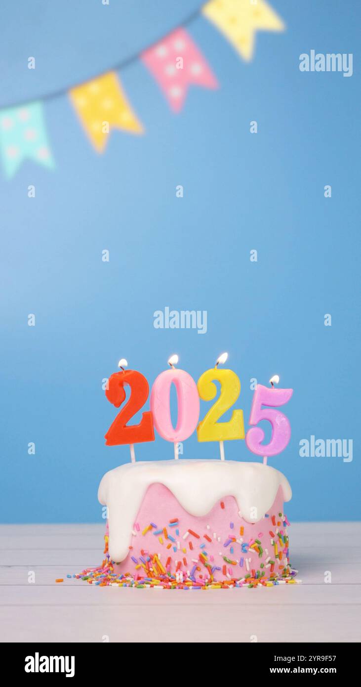 Happy New Year 2025, süßer Kuchen mit bunter Kerze Nummer 2025 für Neujahrsfeier wurde angezündet. Flamme am Kerzenwickel mit blauem Hintergrund Stockfoto