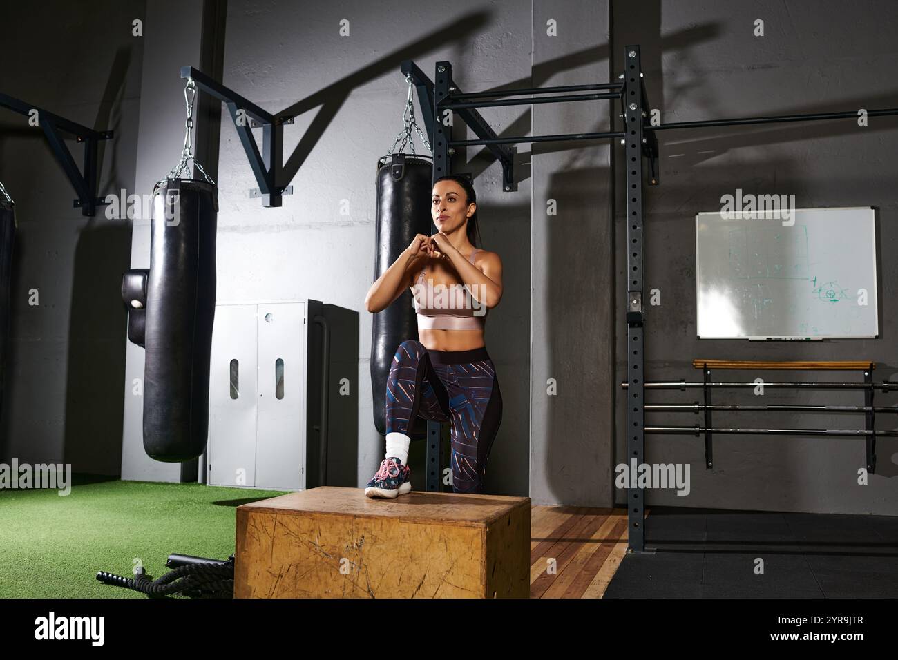 Eine engagierte Frau führt eine Aufstiegsbohrung auf einer robusten Box durch, die Stärke und Beweglichkeit verbessert. Stockfoto