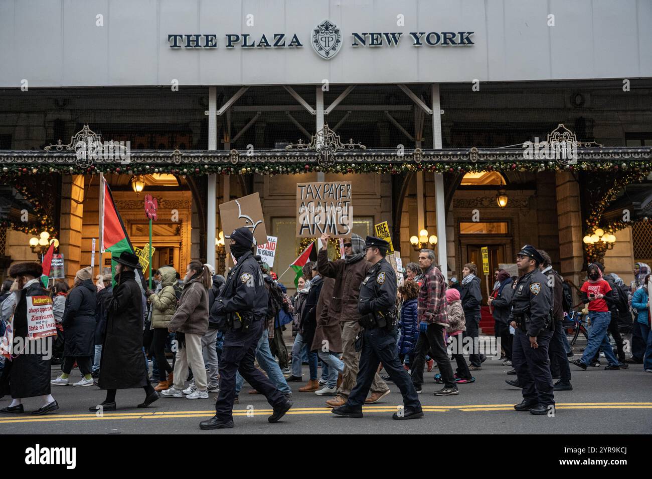 Ein Mann hält vor dem Plaza Hotel ein Schild mit der Aufschrift "Tax Payer Against Arms". Hunderte pro-palästinensischer Demonstranten versammeln sich am Columbus Circle zum "Internationalen Tag der Solidarität für das palästinensische Volk" in New York City. (Foto: Derek French / SOPA Images/SIPA USA) Stockfoto