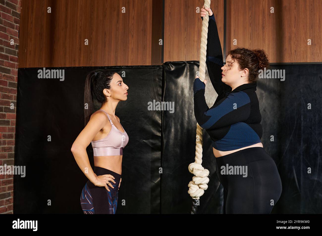 Frauen treiben sich gegenseitig an, um sich in einer anspruchsvollen Fitness-Routine mit Seilklettern zu übertreffen. Stockfoto