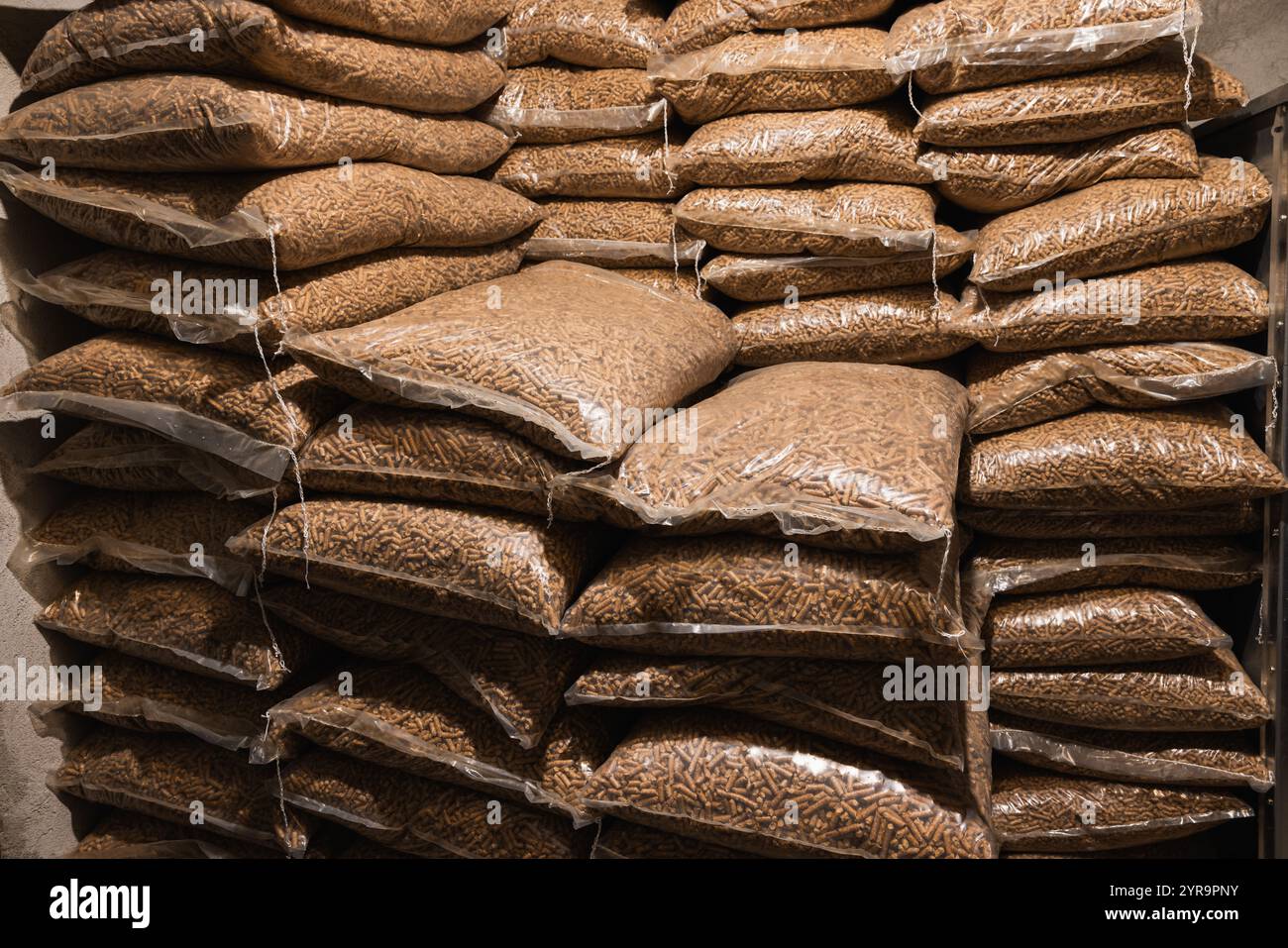 Holzpellets, verpackt in 15-kg-Beuteln. Holzpellets in Plastiktüten gestapelt. Heizöl wird dem Haushalt zur Heizung des Innenraums im Winter zugeführt. Stockfoto