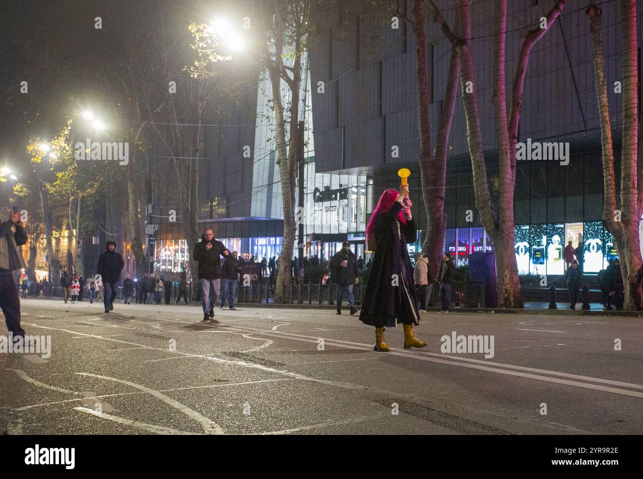 12-1-2024 tiflis ge Junge Frau mit roten Haaren BLASEN THW VUVUZELA - Protest gegen unehrliche Wahlen im georgischen parlament Stockfoto