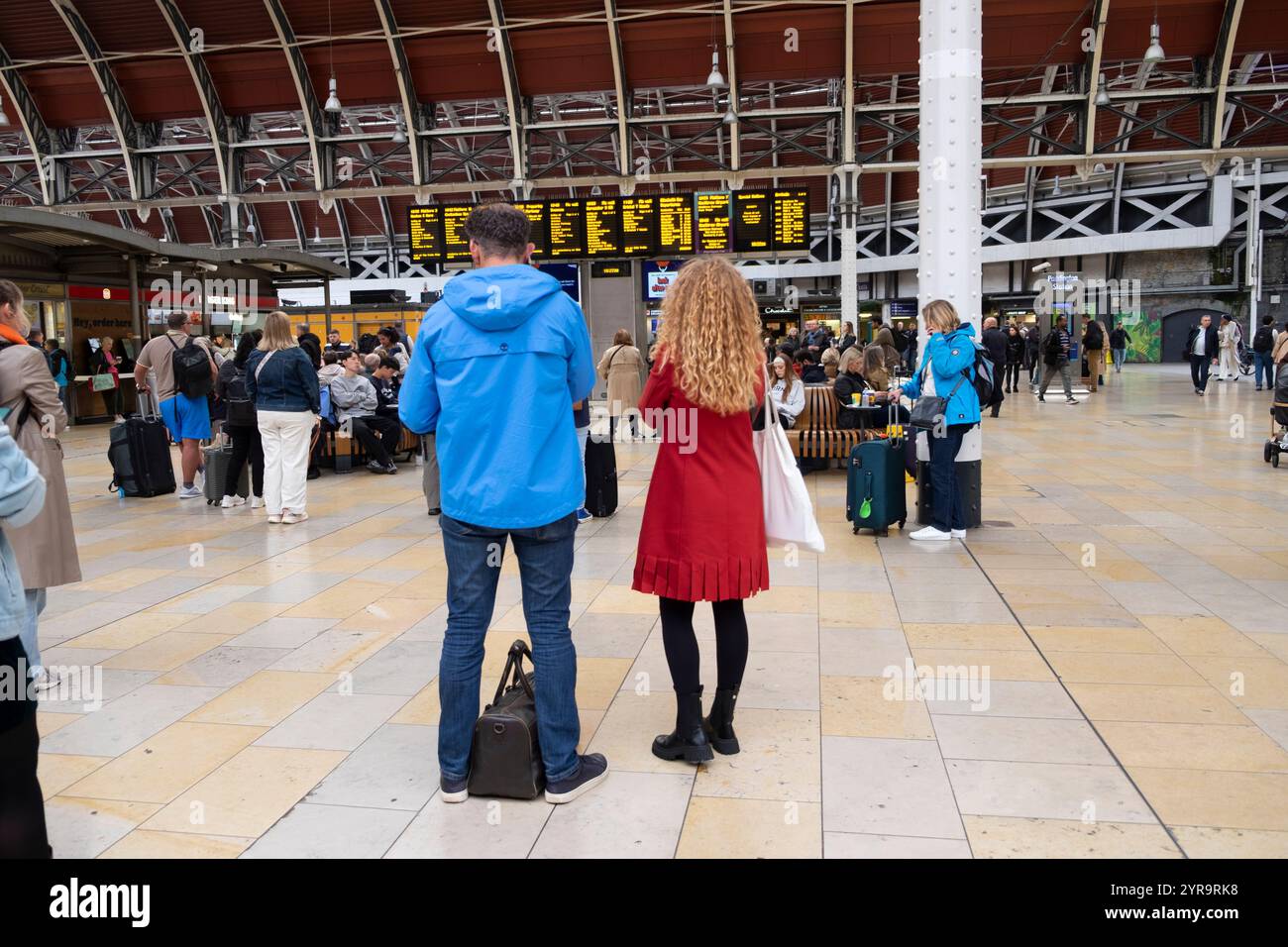 Rückansicht von Personen, die auf die elektronische Reiseinformationstafel in Paddington Station schauen Oktober 2024 London England Großbritannien KATHY DEWITT Stockfoto