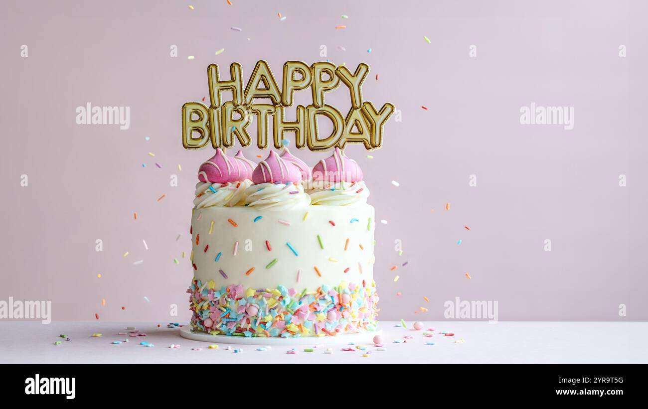Rosa Geburtstagskuchen mit goldenem Happy Birthday Banner und bunten Streuseln Stockfoto