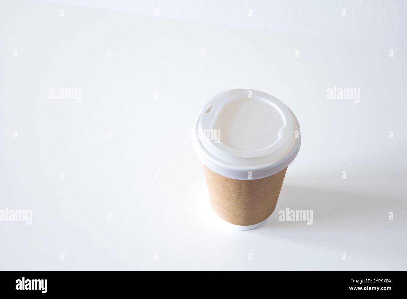 Leere, generische Kaffeetasse zum Mitnehmen aus Kunststoff mit brauner Papierverpackung, isoliert auf weiß. Nahaufnahme, kein Branding, keine Logos, keine Leute. Stockfoto