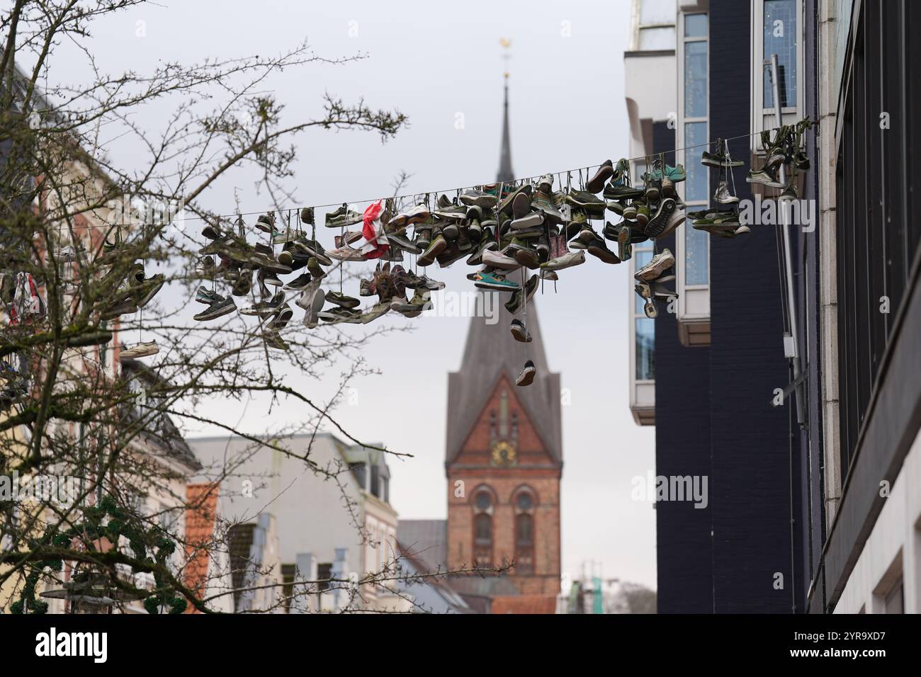 Flensburg, Deutschland. Dezember 2024. Schuhe hängen an einem Drahtseil oberhalb der Norderstraße. Quelle: Marcus Brandt/dpa/Alamy Live News Stockfoto