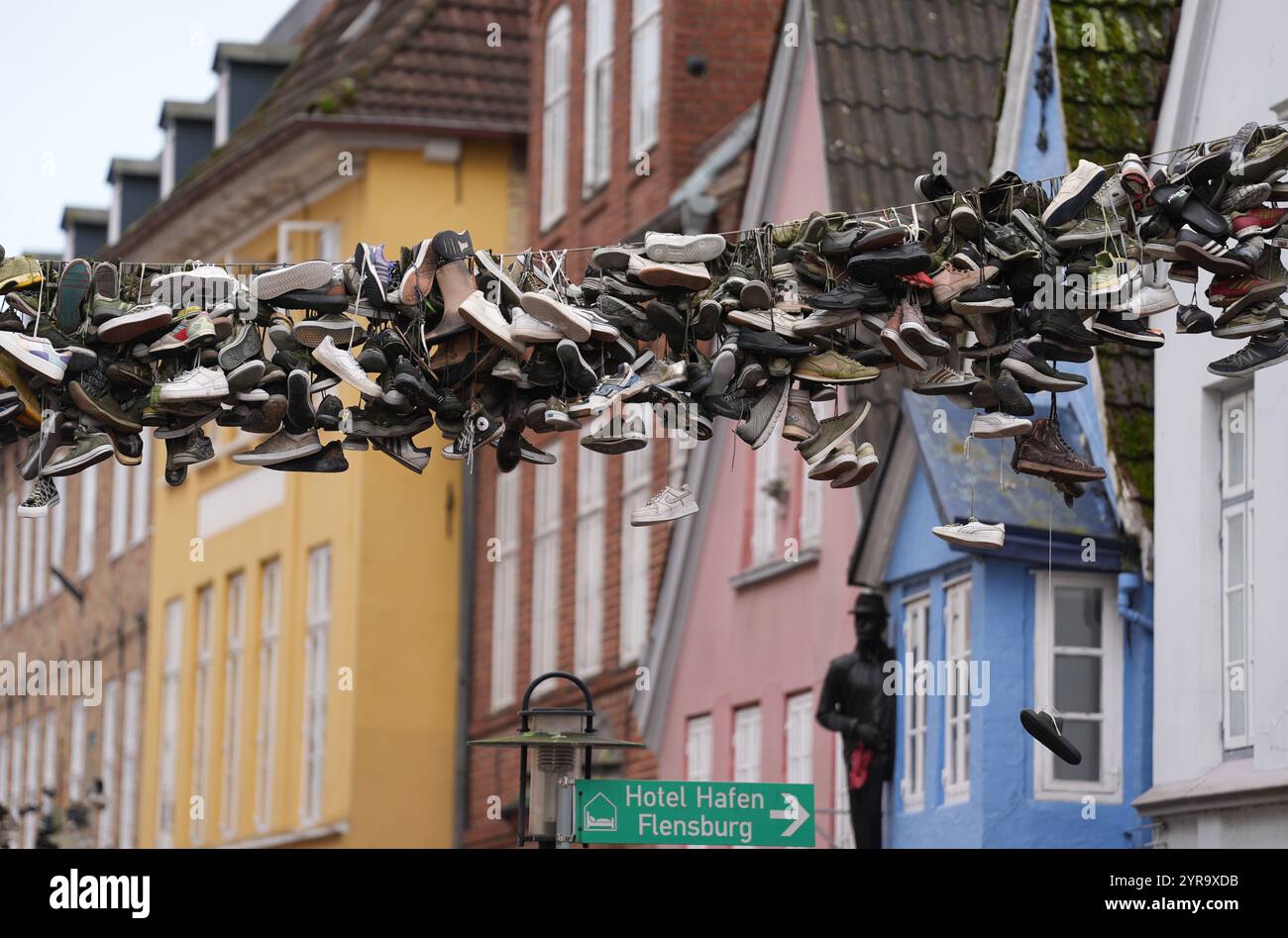 Flensburg, Deutschland. Dezember 2024. Schuhe hängen an einem Drahtseil oberhalb der Norderstraße. Quelle: Marcus Brandt/dpa/Alamy Live News Stockfoto