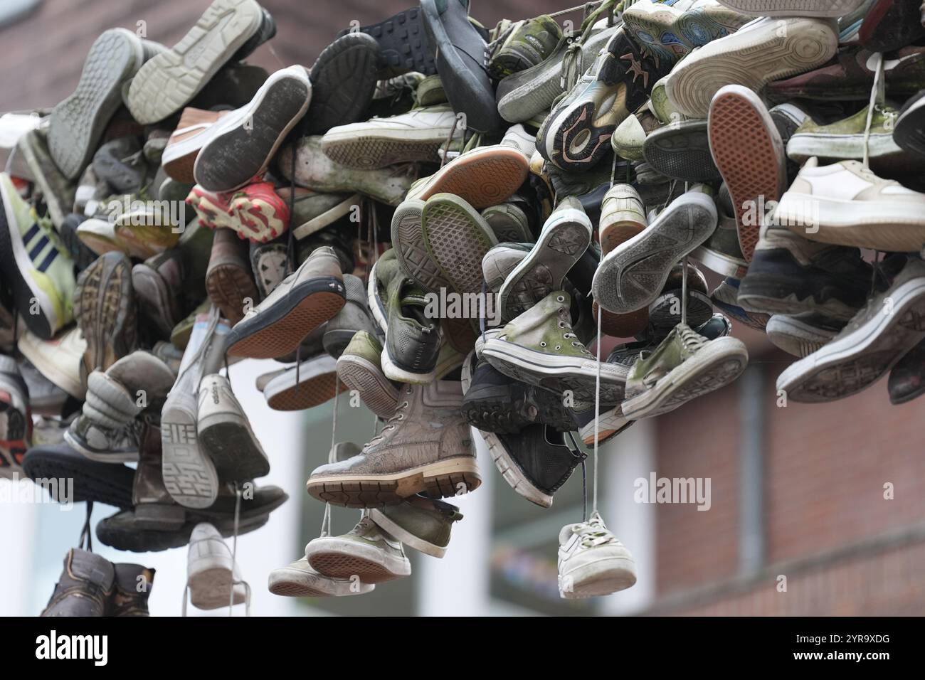Flensburg, Deutschland. Dezember 2024. Schuhe hängen an einem Drahtseil oberhalb der Norderstraße. Quelle: Marcus Brandt/dpa/Alamy Live News Stockfoto