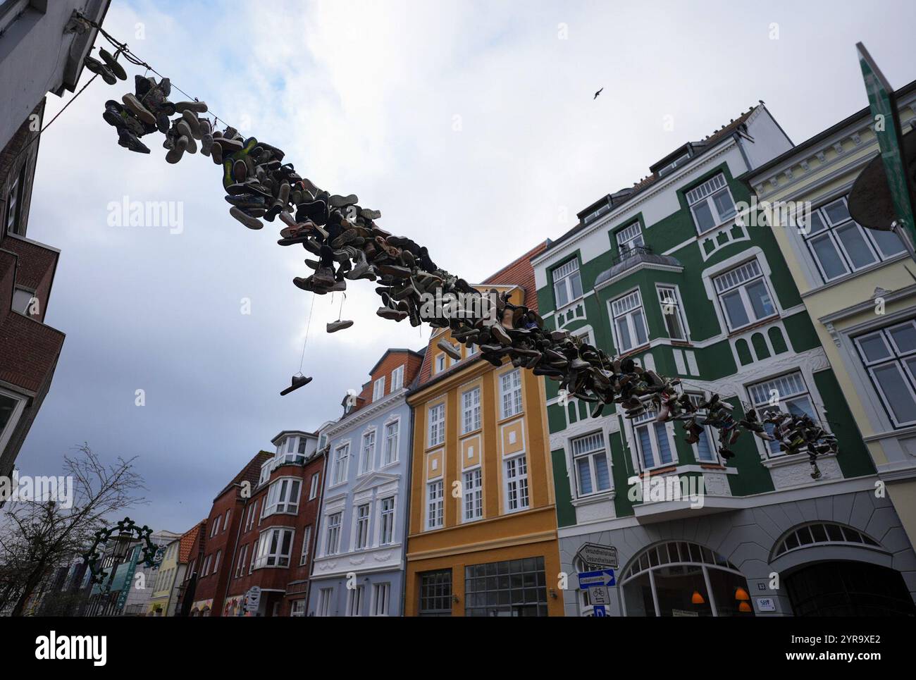 Flensburg, Deutschland. Dezember 2024. Schuhe hängen an einem Drahtseil oberhalb der Norderstraße. Quelle: Marcus Brandt/dpa/Alamy Live News Stockfoto