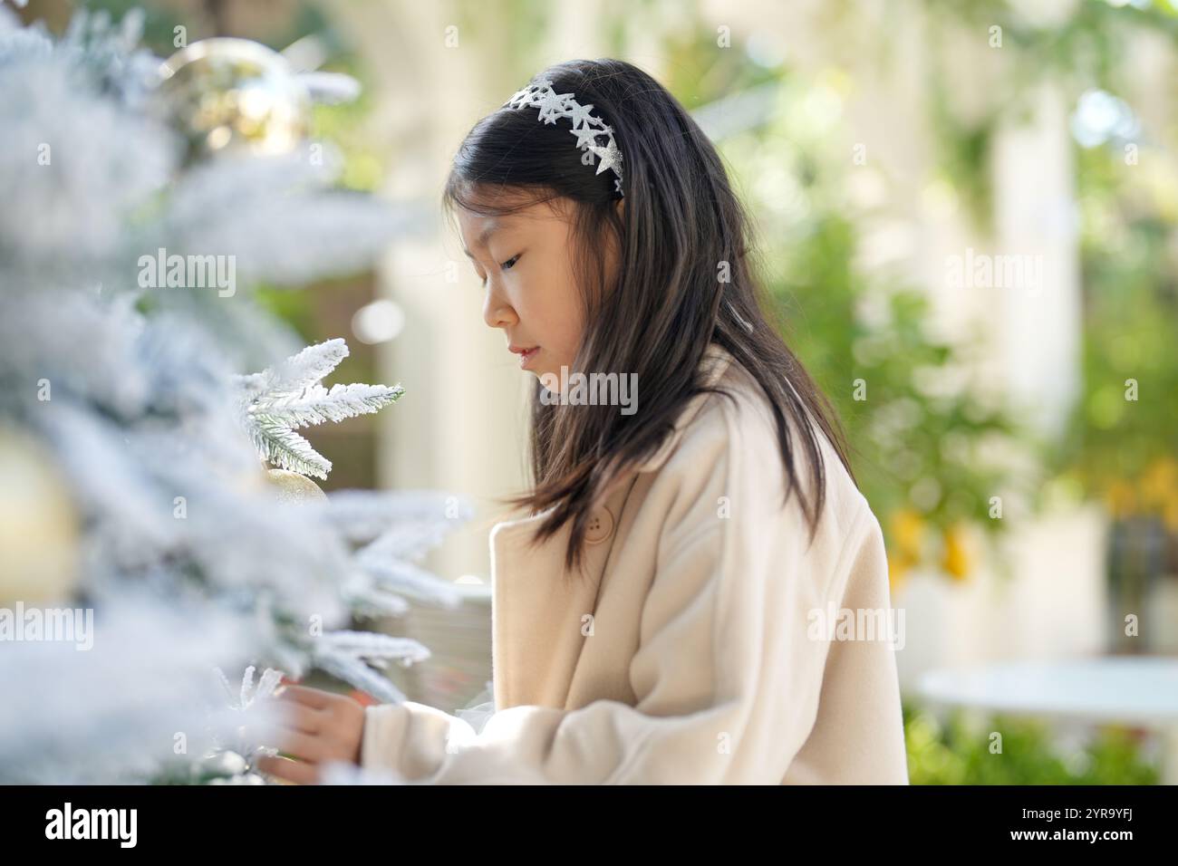 Eine 9-jährige Singapurin schmückt den Weihnachtsbaum in einem schönen Weihnachtscafé in der Innenstadt von Shanghai, China. Stockfoto Eine 9-jährige Singapurin schmückt den Weihnachtsbaum in einem schönen Weihnachtscafé in der Innenstadt von Shanghai, China. Stockfoto