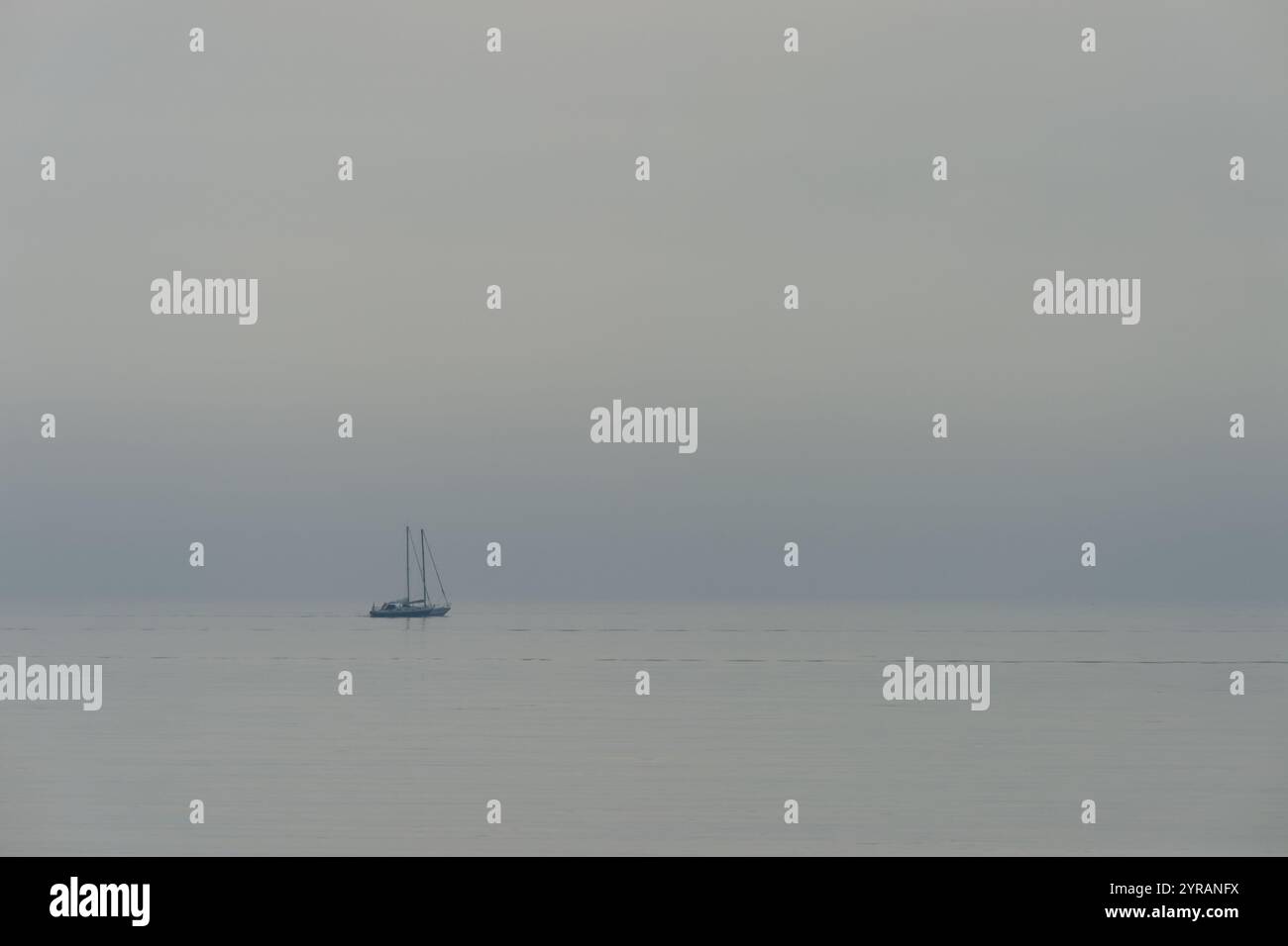 Einfarbiges Bild der Silhouette eines kleinen fischerbootes mit zwei Masten ohne Takelage an der Ostsee in Schönhagen, Kieler Bucht Stockfoto