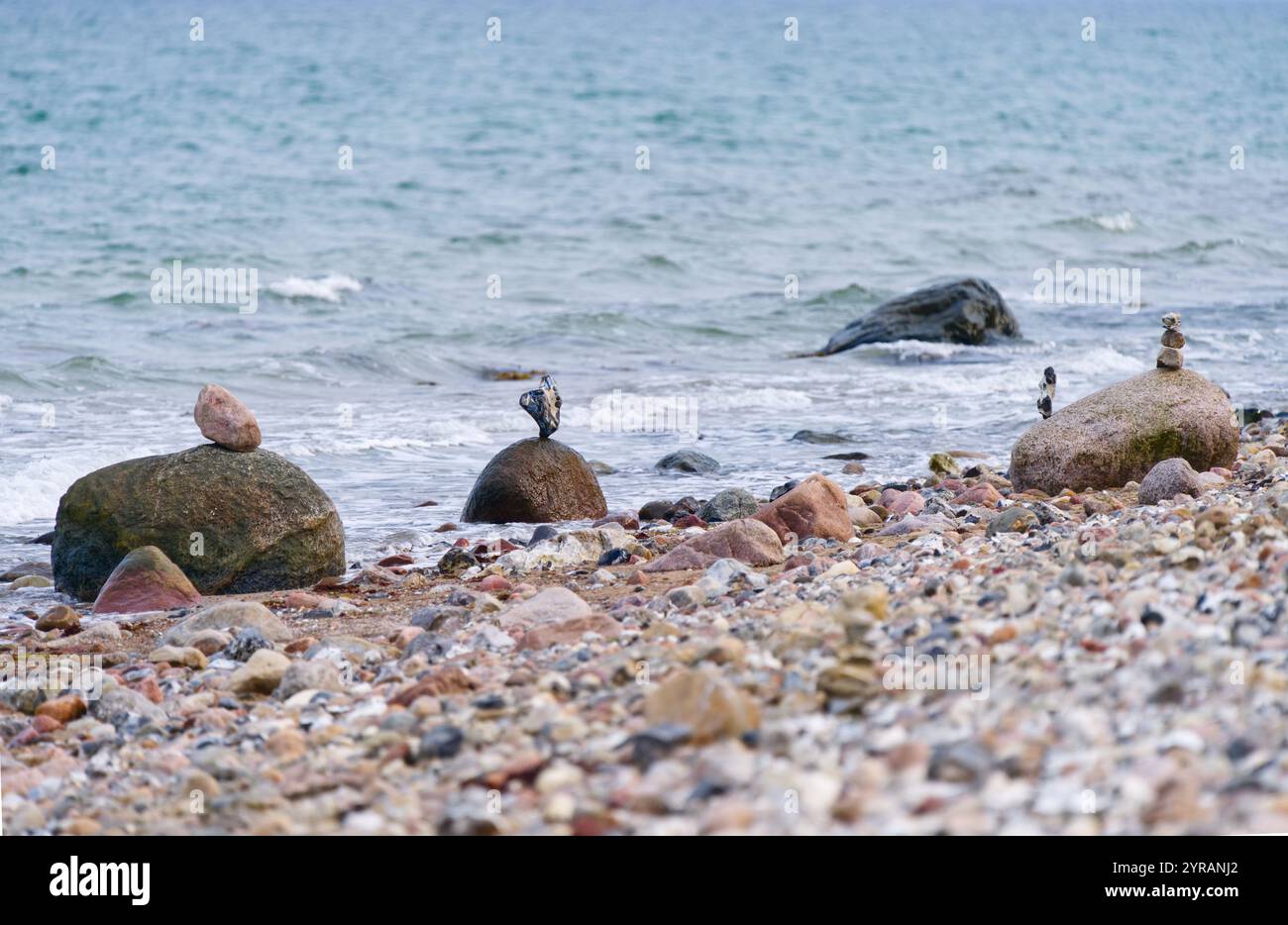 Eine Reihe angeordneter Steinhaufen entlang der Küstenlinie am Kiesstrand der Ostsee, die Harmonie und einen ausgewogenen Lebensstil darstellen Stockfoto