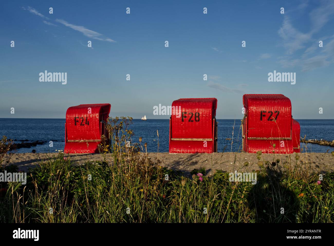 Blick auf die Ostsee durch rote gedeckte Korbstühle am Sandstrand von Schönhagen, Kieler Bucht, Schleswig-Holstein, Deutschland Stockfoto