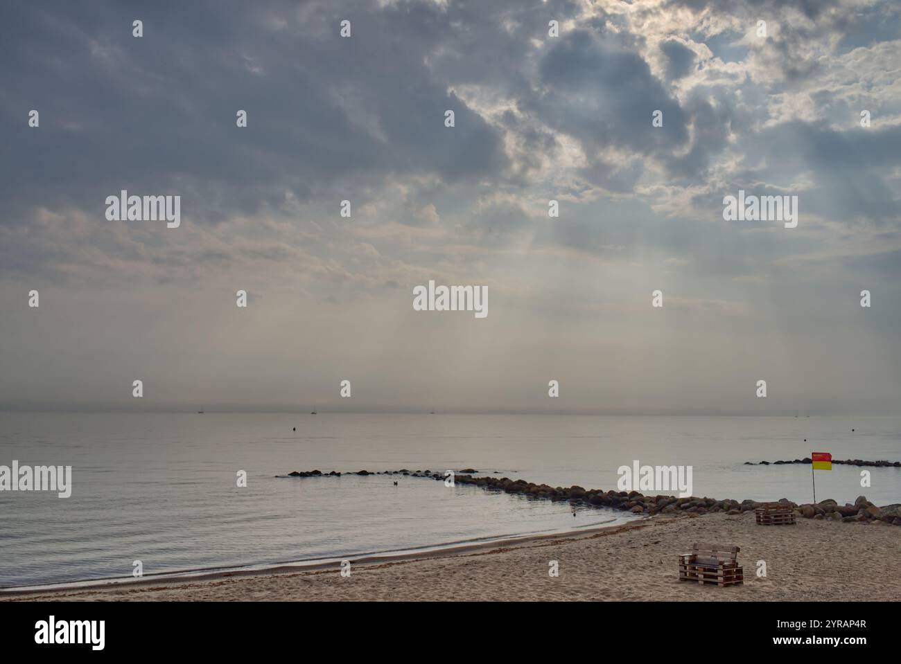 Blick vom Strand an die Ostsee und eine Steingroyne bei bewölktem Wetter, aber mit Lichtstrahlen auf Schönhagen, Kieler Bucht, Deutschland Stockfoto