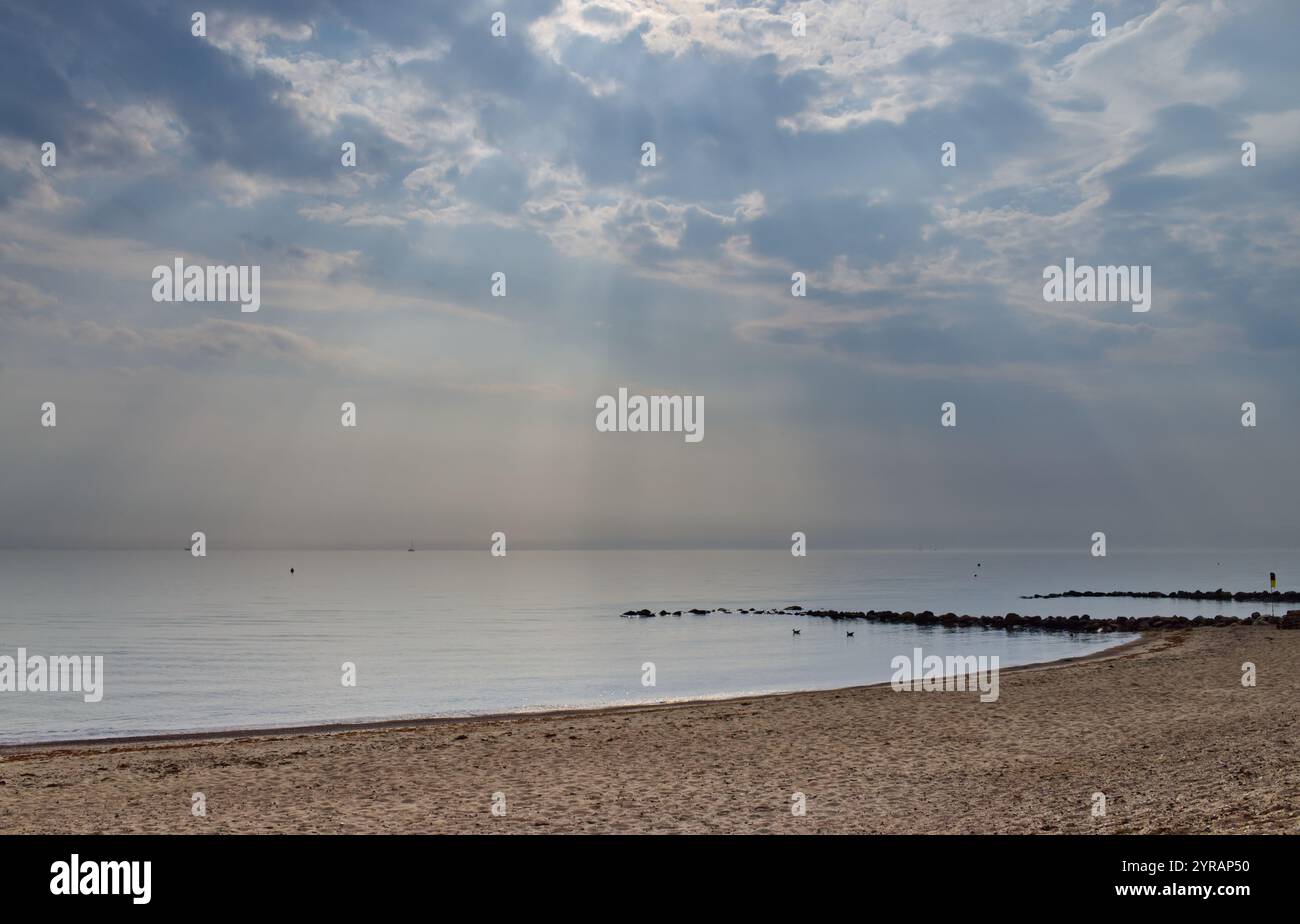Blick vom Sandstrand an der Ostsee und einer Steingroyne bei bewölktem Wetter, aber mit Lichtstrahlen in Schönhagen, Kieler Bucht Stockfoto