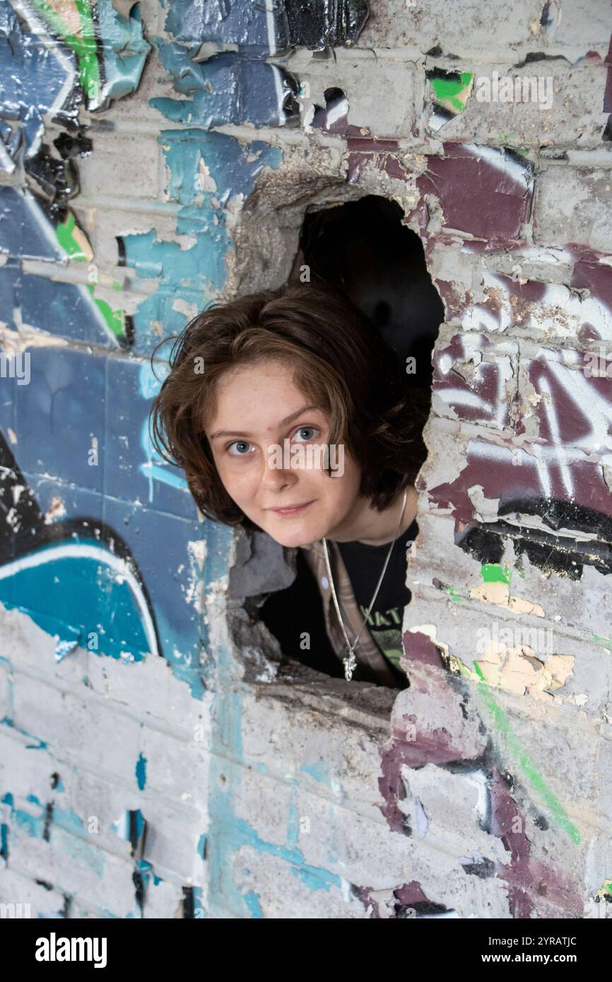 Yorkshire, Großbritannien: 31. Mai 2024 – der Kopf Eines Teenagers, der durch ein Loch in der Graffiti-bedeckten Wand des vernachlässigten Castle College Sportplatzes chang stochelt Stockfoto