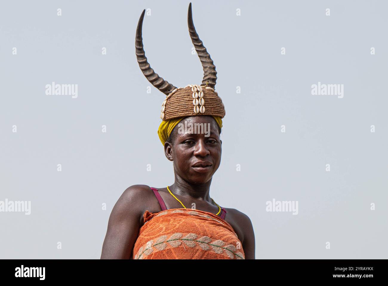 Frau in traditioneller Tracht mit Gehörntem Hut lächelnd in einem ländlichen Dorf in Togo Stockfoto