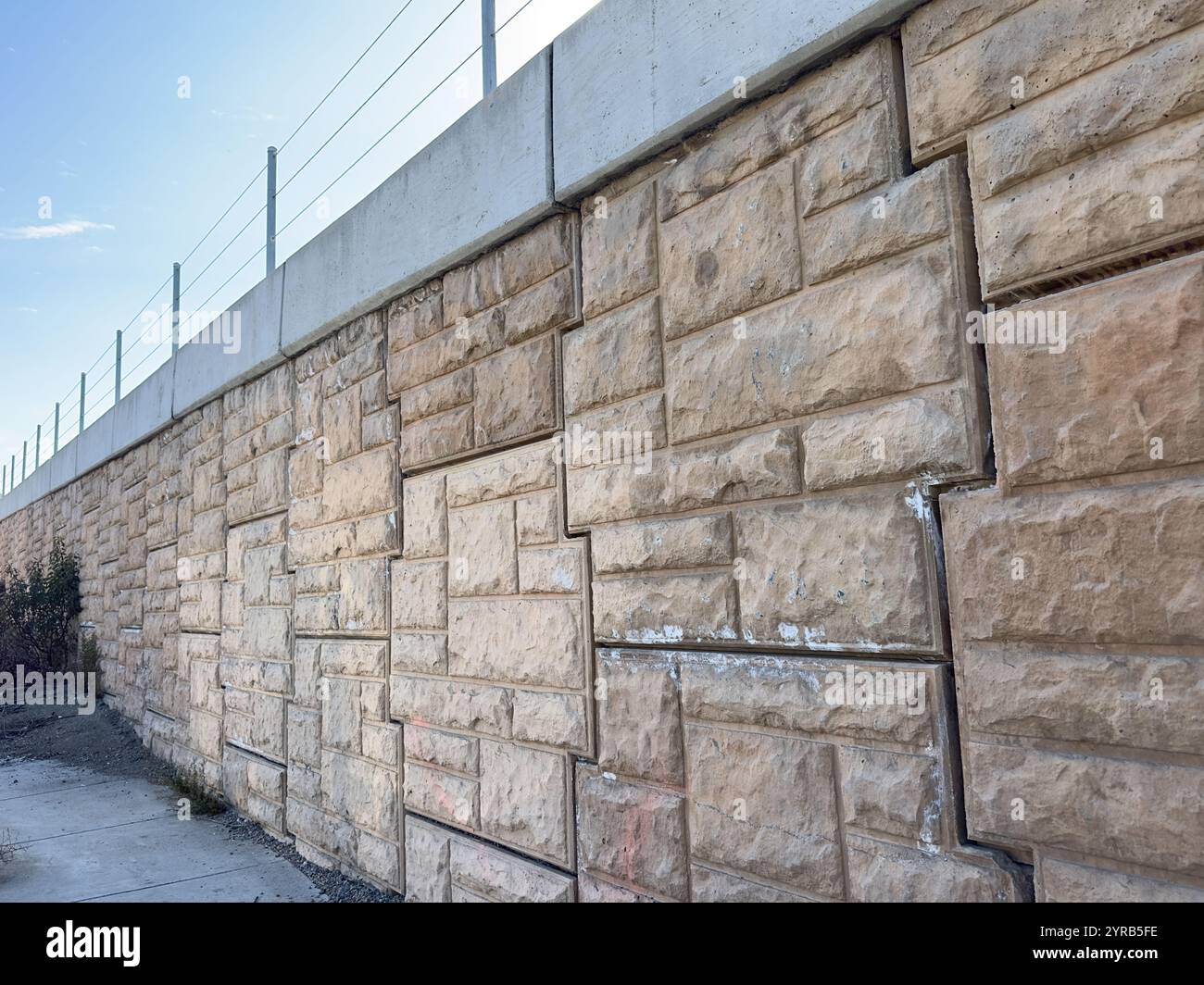 Die komplizierten Muster und Schichten einer Betonmauer, die dem Stadtbild ein visuelles Interesse verleiht. - Smartphone-aufgenommenes Stockfoto