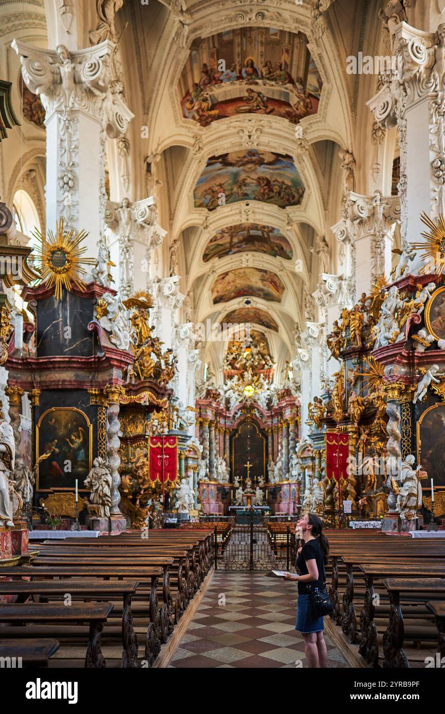 Eine Frau steht in Ehrfurcht und blickt nach oben in einer wunderschön verzierten Kirche in Neuzelle, umgeben von komplizierten Statuen und detaillierter Architektur. Stockfoto