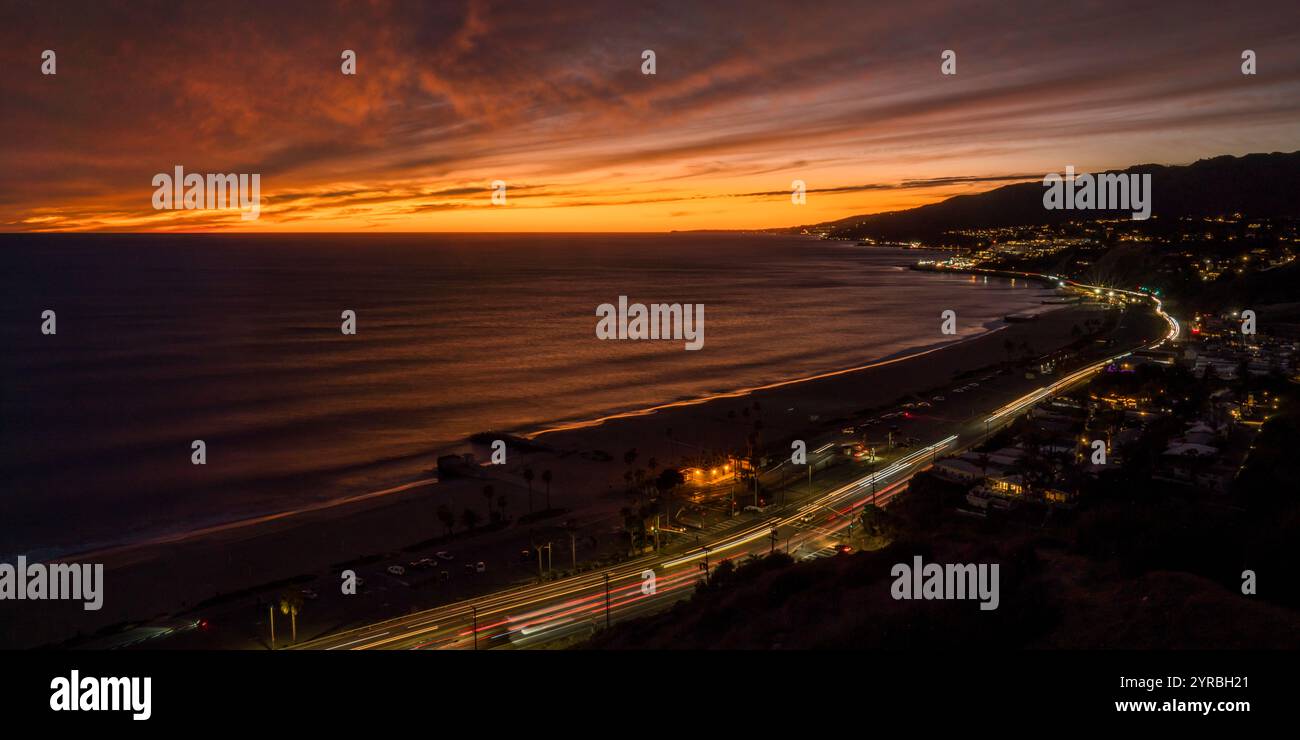 10. JANUAR 2022, PACIFIC PALISADES, LOS ANGELES, USA - Sonnenuntergang an der Santa Monica Bay in Richtung Malibu vom Pacific Palisades Bluff Park zeigt den Verkehr auf der Route 1 Pacific Coast Highway Stockfoto