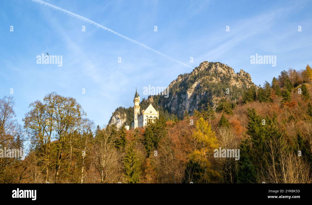 Bayern, Deutschland. Das märchenhafte Schloss Neuschwanstein in den bayerischen Alpen. Malerischer Blick auf grüne Waldbäume, Sonnenaufgangshimmel am See mit Wolken. Stockfoto