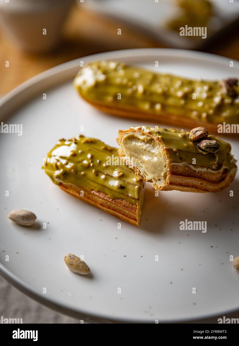 Pistazien-Eclairs mit hellgrüner Glasur auf weißer Platte Stockfoto