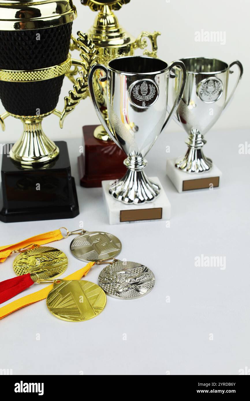 Eine Sammlung von Trophäen und Medaillen, die elegant auf einem Tisch angeordnet sind und Erfolge und Anerkennung auf eine besondere Weise darstellen Stockfoto