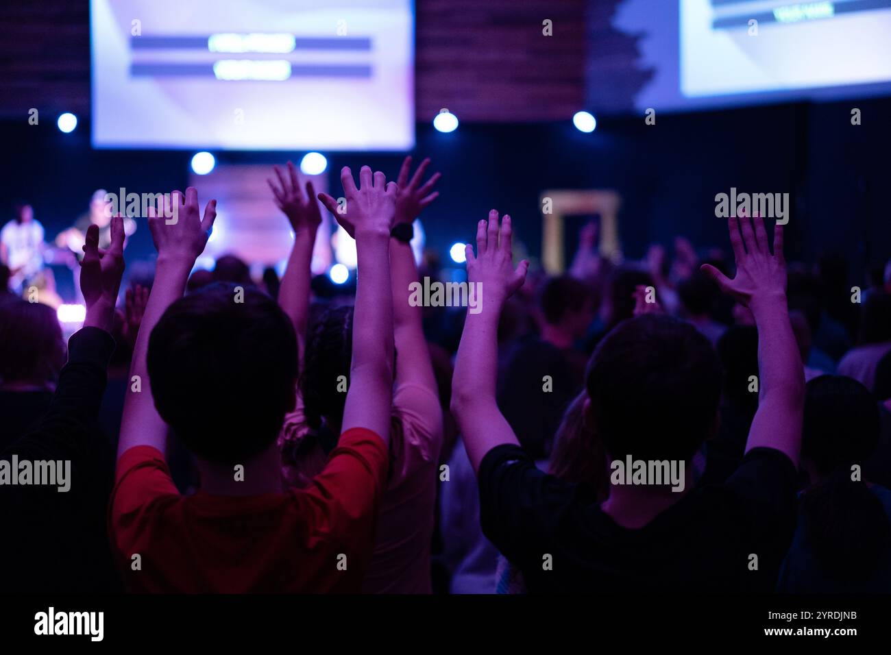 Teenager, die mit erhobenen Händen in einem Konzert anbeten Stockfoto