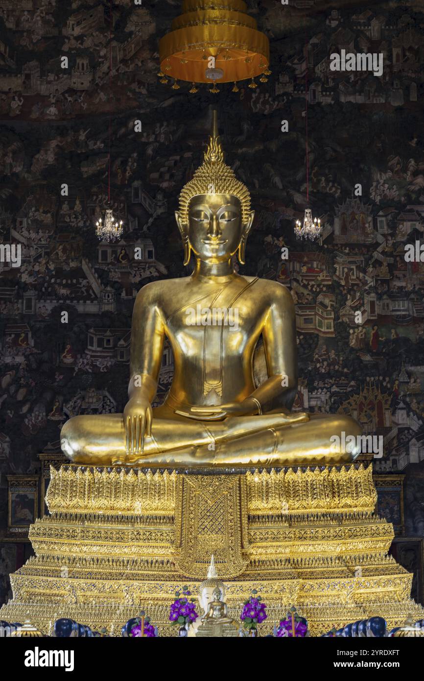 Goldene Buddha-Statue, Phra Buddha Trilokachet, umgeben von exquisiten Wandmalereien, Innenansicht des Phra Ubosot oder der Ordinationshalle, Wat Suthat Thepwar Stockfoto