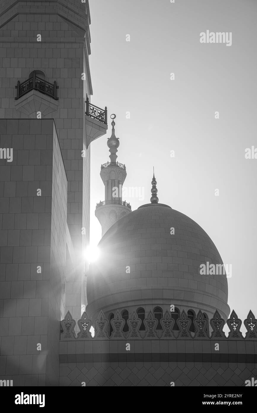 Schwarzweiß-Foto der Kuppel und des Minaretts der Scheich-Zayed-Moschee in Abu Dhabi, mit Sonnenlicht, das die komplizierte islamische Architektur hervorhebt. Stockfoto