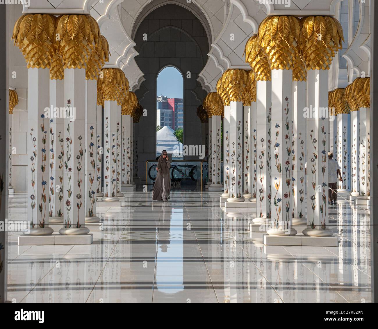 Reich verzierter Innenkorridor der Scheich-Zayed-Moschee mit goldenen, palmenförmigen Kapitellen und Marmorblumensäulen in Abu Dhabi, VAE. Stockfoto