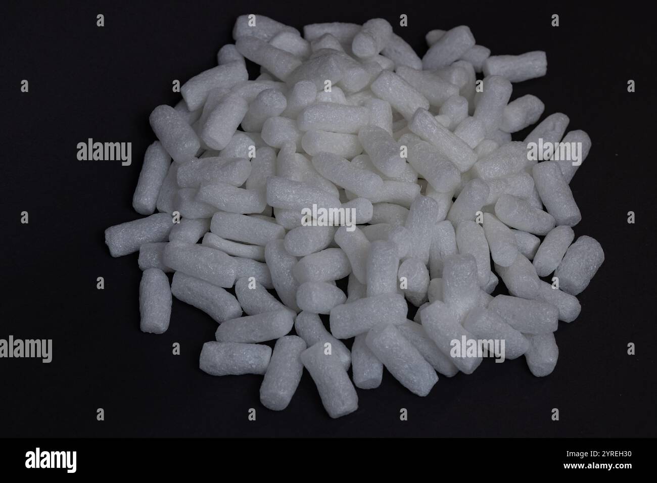 Nahaufnahme von weißen biologisch abbaubaren Erdnüssen, die auf einem Stapel auf schwarzem Hintergrund angeordnet sind. Nachhaltige Verpackungsmaterialien und umweltfreundliche Lösungen Stockfoto