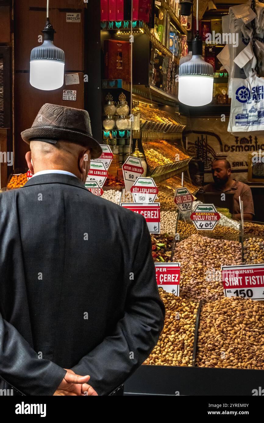 Ein älterer türkischer Mann blickt auf eine Ladenfront, die Lebensmittel verkauft und die lokale Kultur, Tradition und eine Verbindung zum Alltag widerspiegelt. Stockfoto