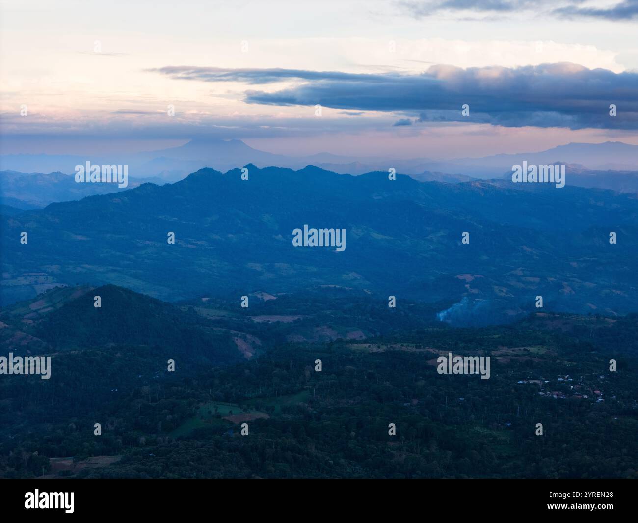 Die Abenddämmerung lässt sich über eine ruhige Berglandschaft nieder und enthüllt weit entfernte Gipfel unter farbenfrohen Himmel, die eine ruhige Atmosphäre schaffen. Stockfoto