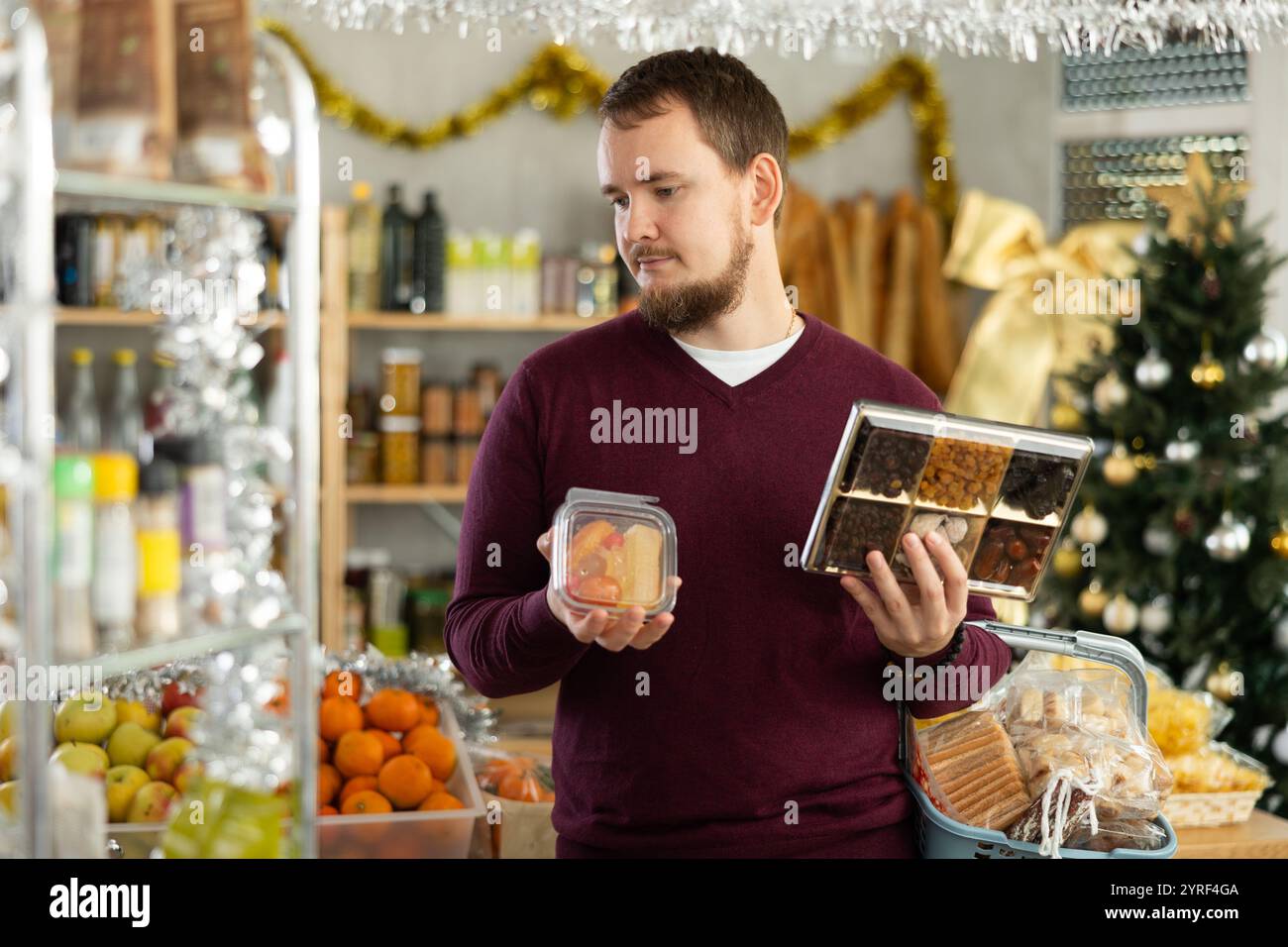 Ein Mann, der Süßigkeiten und getrocknete Früchte für ein Festmahl im Lebensmittelgeschäft auswählt Stockfoto